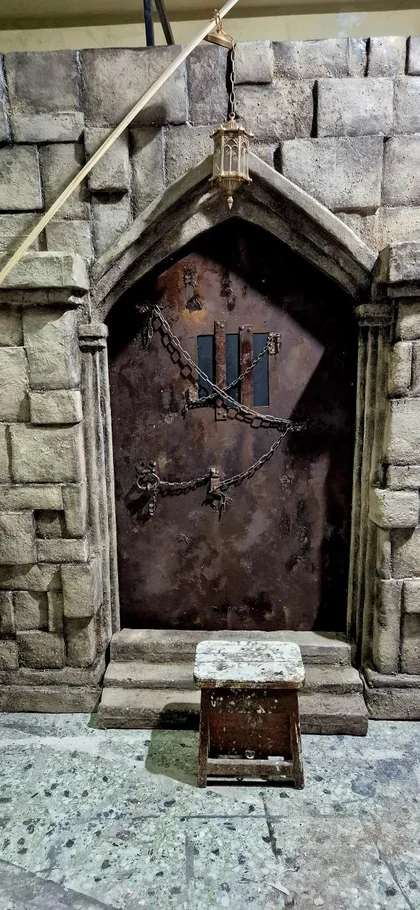 Frontal view of a Gothic-style scenic doorway with stone-effect masonry and a chained door.