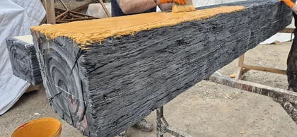 A timber-effect scenic beam being painted in a workshop.