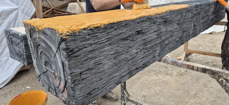 A timber-effect scenic beam being painted in a workshop.